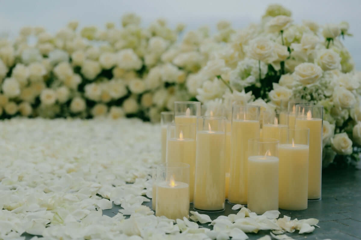 winterwood ember candle surrounded by white roses and rose petals, creating an elegant ambiance.