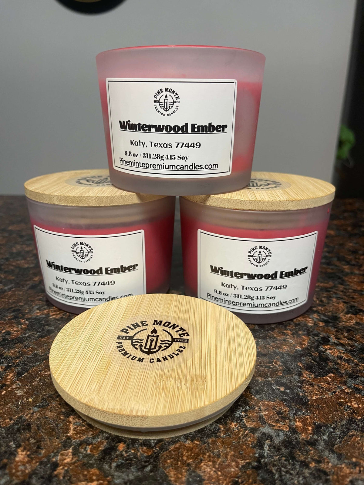 Winter Wood Candle displayed with three jars and wooden lids, showcasing its warm, smoky, cozy fragrance.