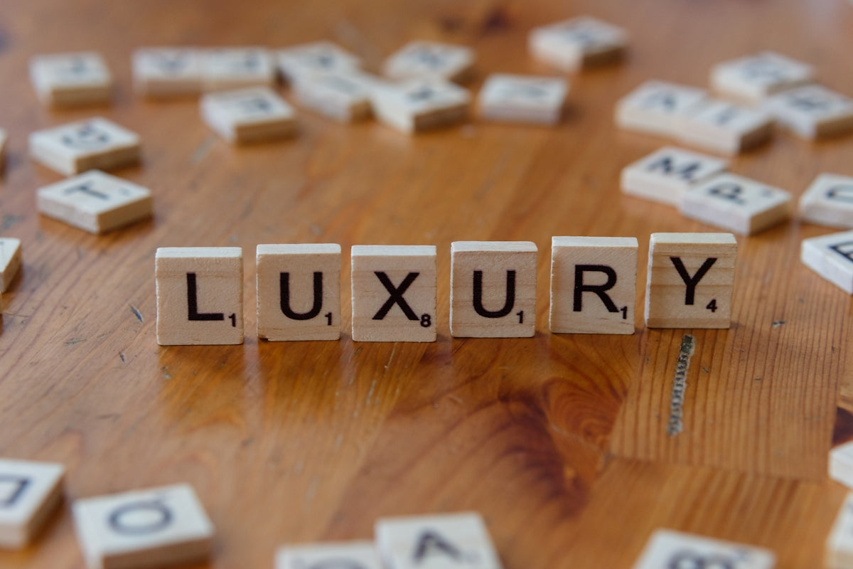 Scrabble tiles spelling the word luxury on a wooden table