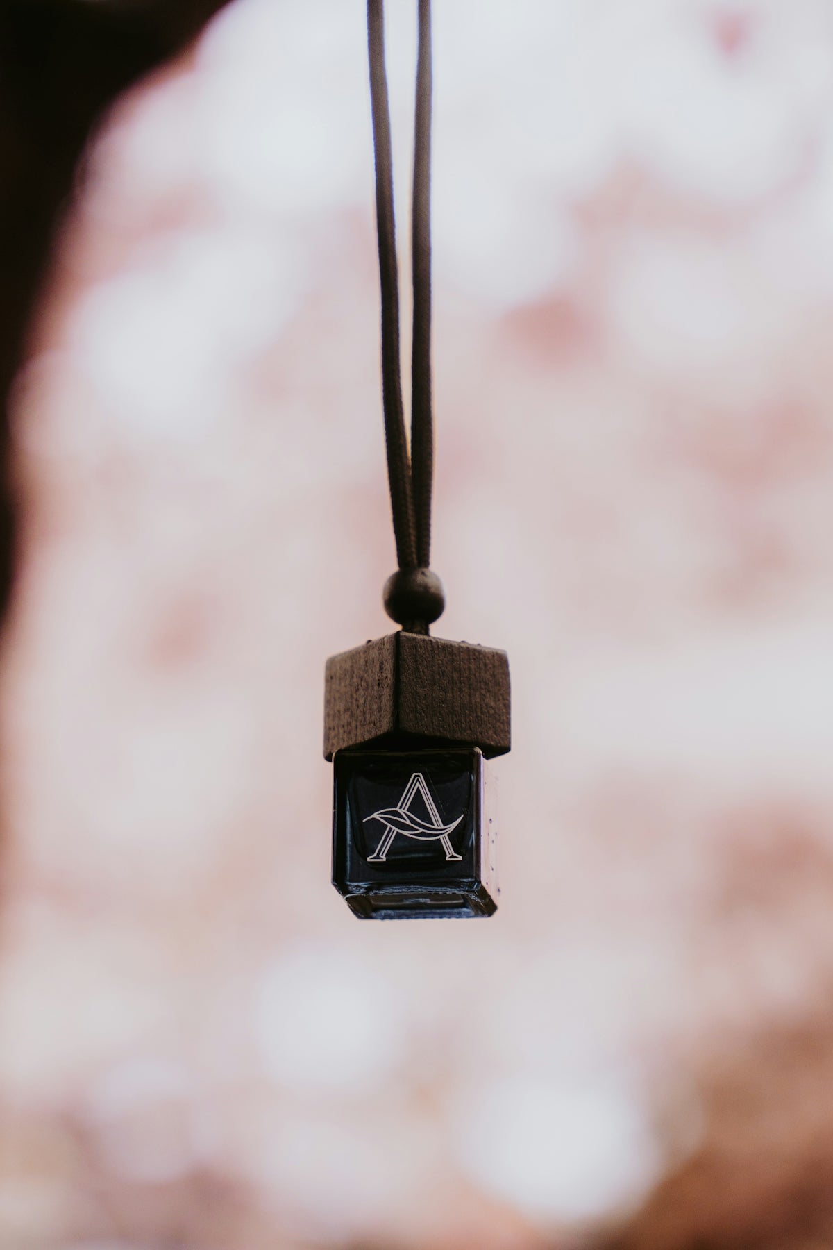 An a charm hangs from a dark string.