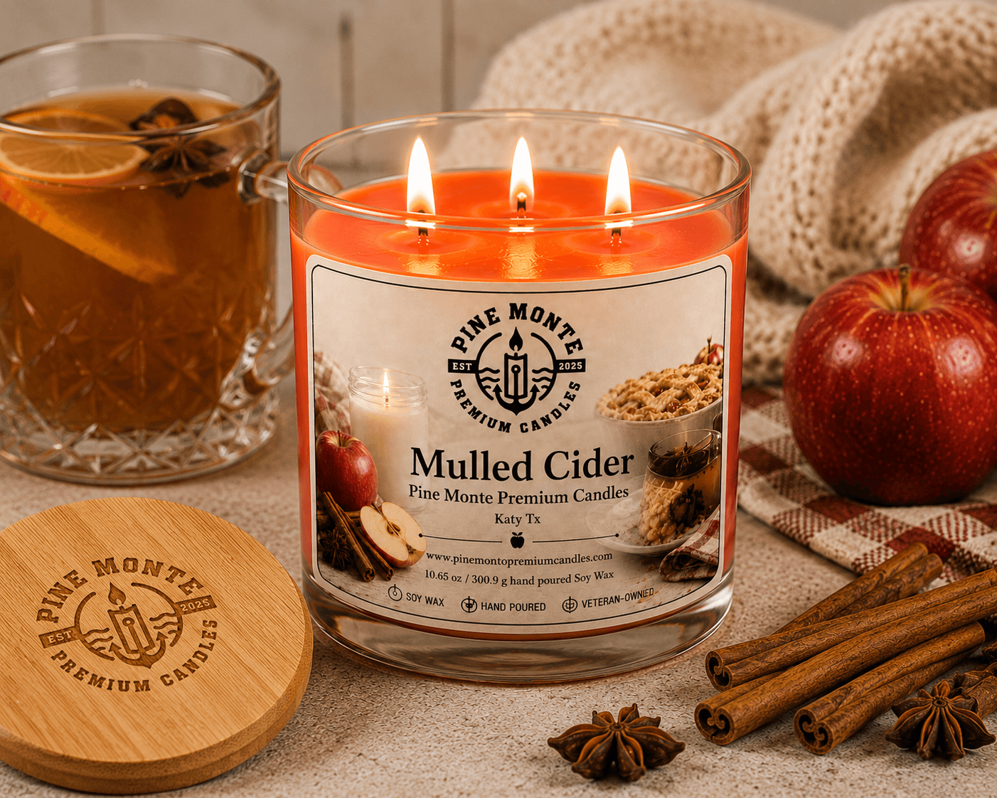 Mulled Cider Soy Candle with a warm glow, surrounded by apples and spices, creating a cozy autumn atmosphere.
