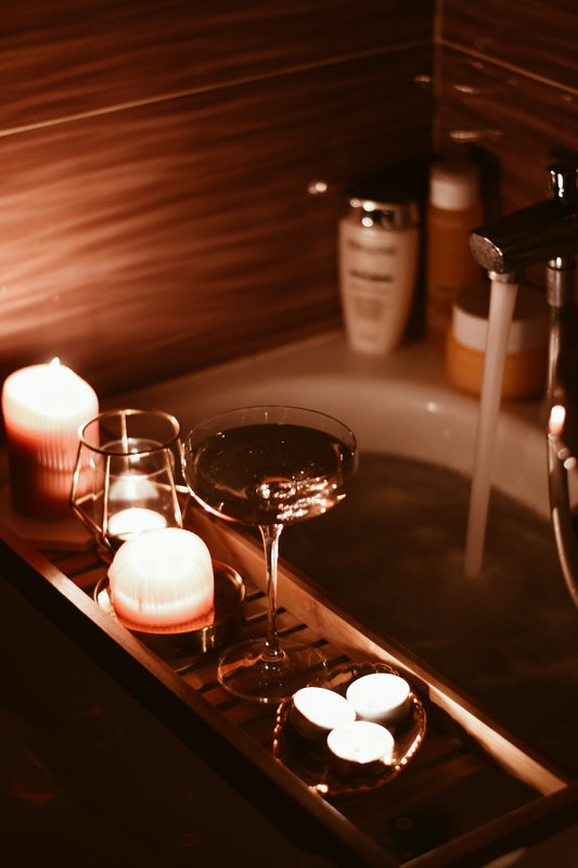 A bath tub filled with candles and a wine glass