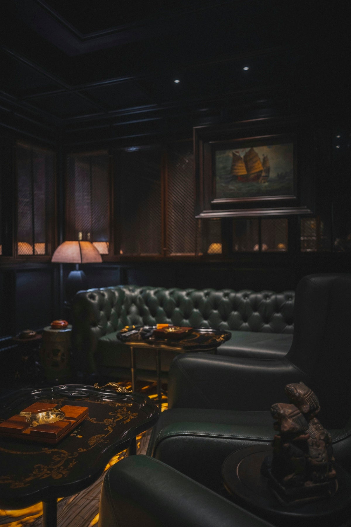 Luxurious dark room with green leather chesterfield sofa.