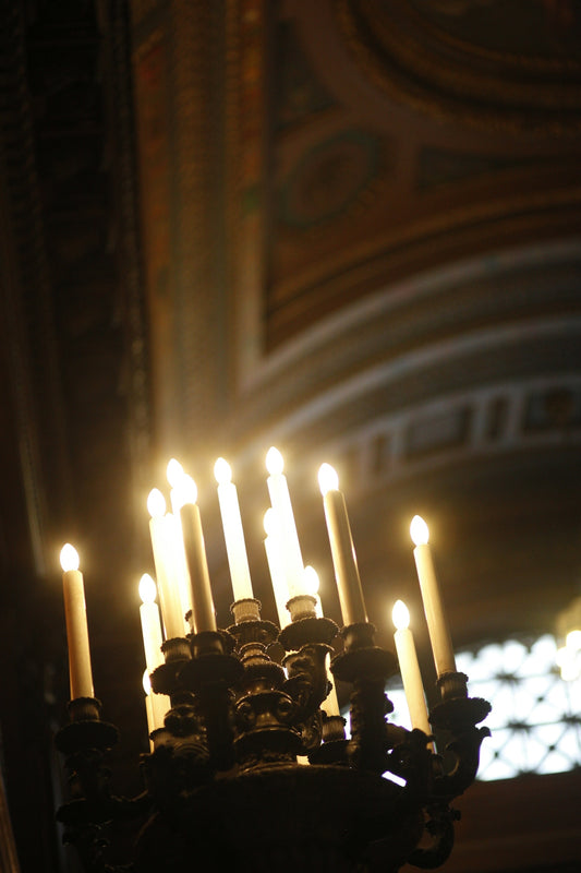 Candles glow in a dark, ornate chandelier.
