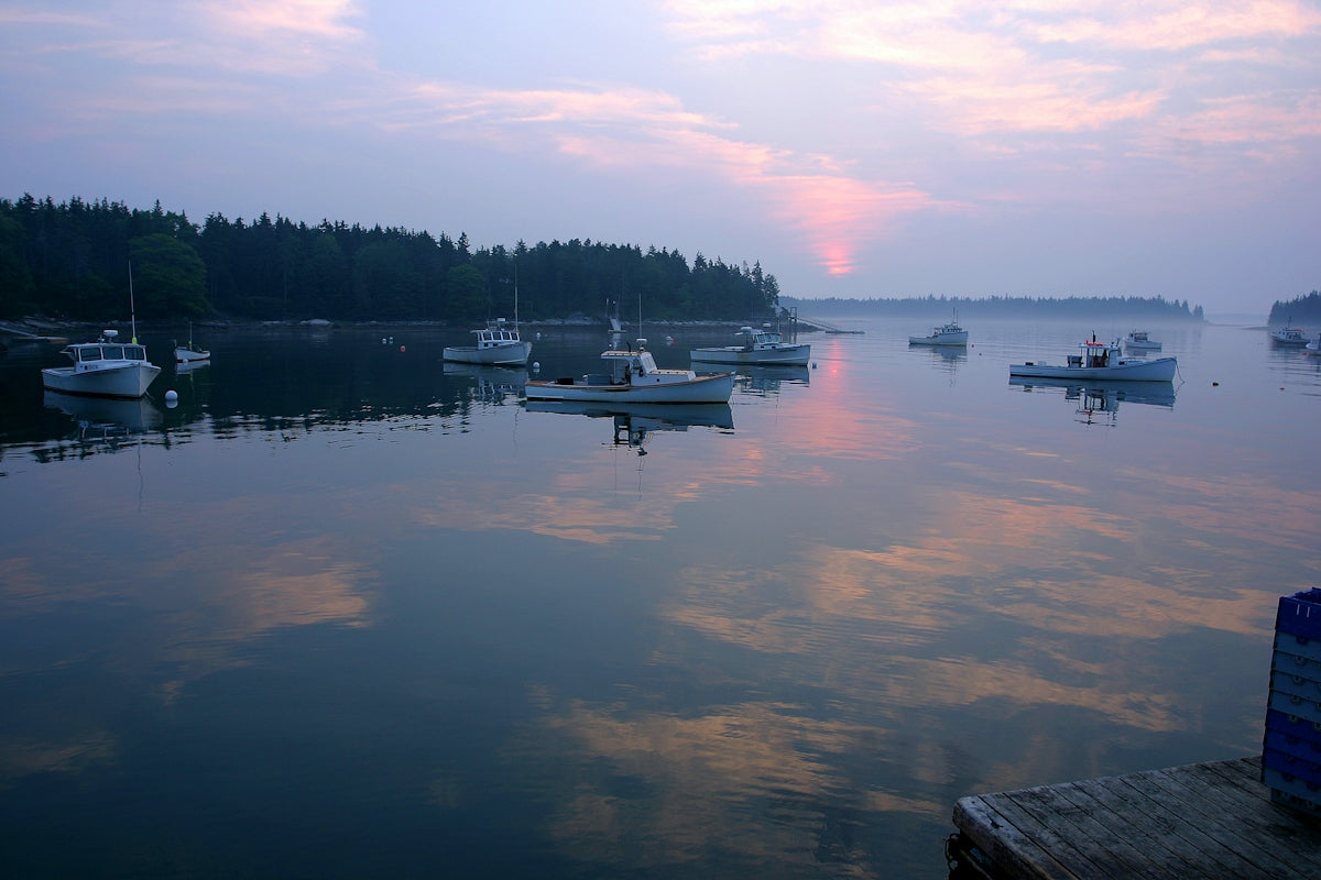 Fishing boats anchored in a calm harbor at sunrise