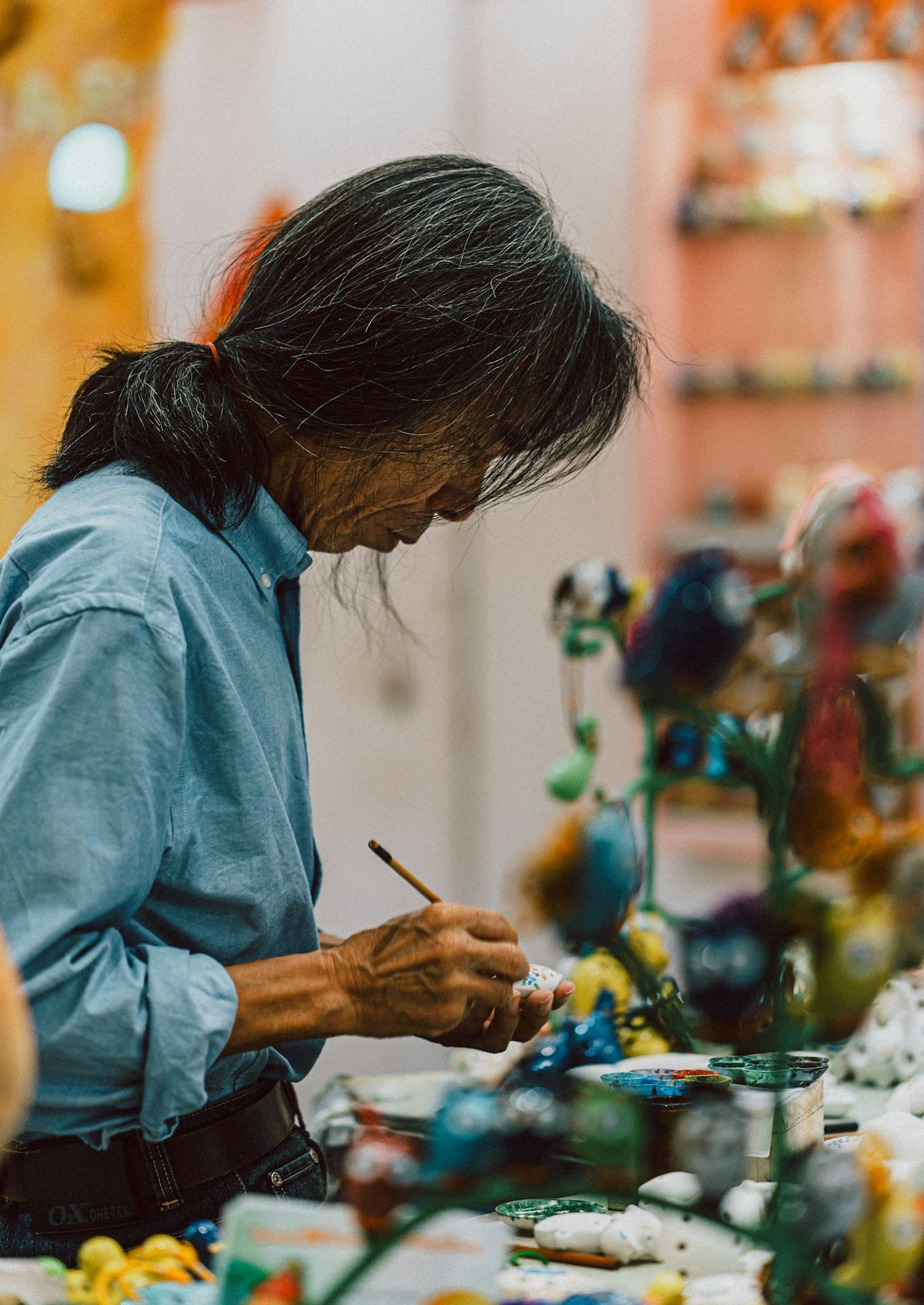 An artist painting small colorful figures with a brush